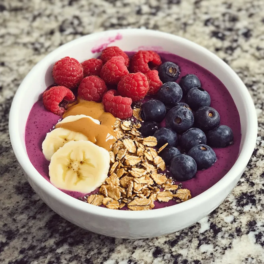 Um bowl com pedaços de banana, framboesas, mirtilos e granola.