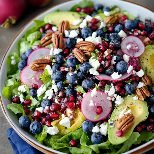 Tigela de salada cheia de mirtilo, abacate e pecãs.