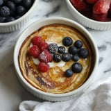 Uma tigela com comida, frutas vermelhas e creme.