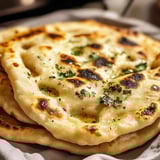 Uma pilha de tortilhas com ervas verdes por cima.