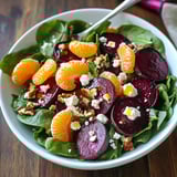 A bowl of salad with oranges and blue cheese.