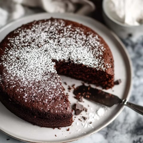 Uma fatia de bolo de chocolate com açúcar polvilhado em um prato.